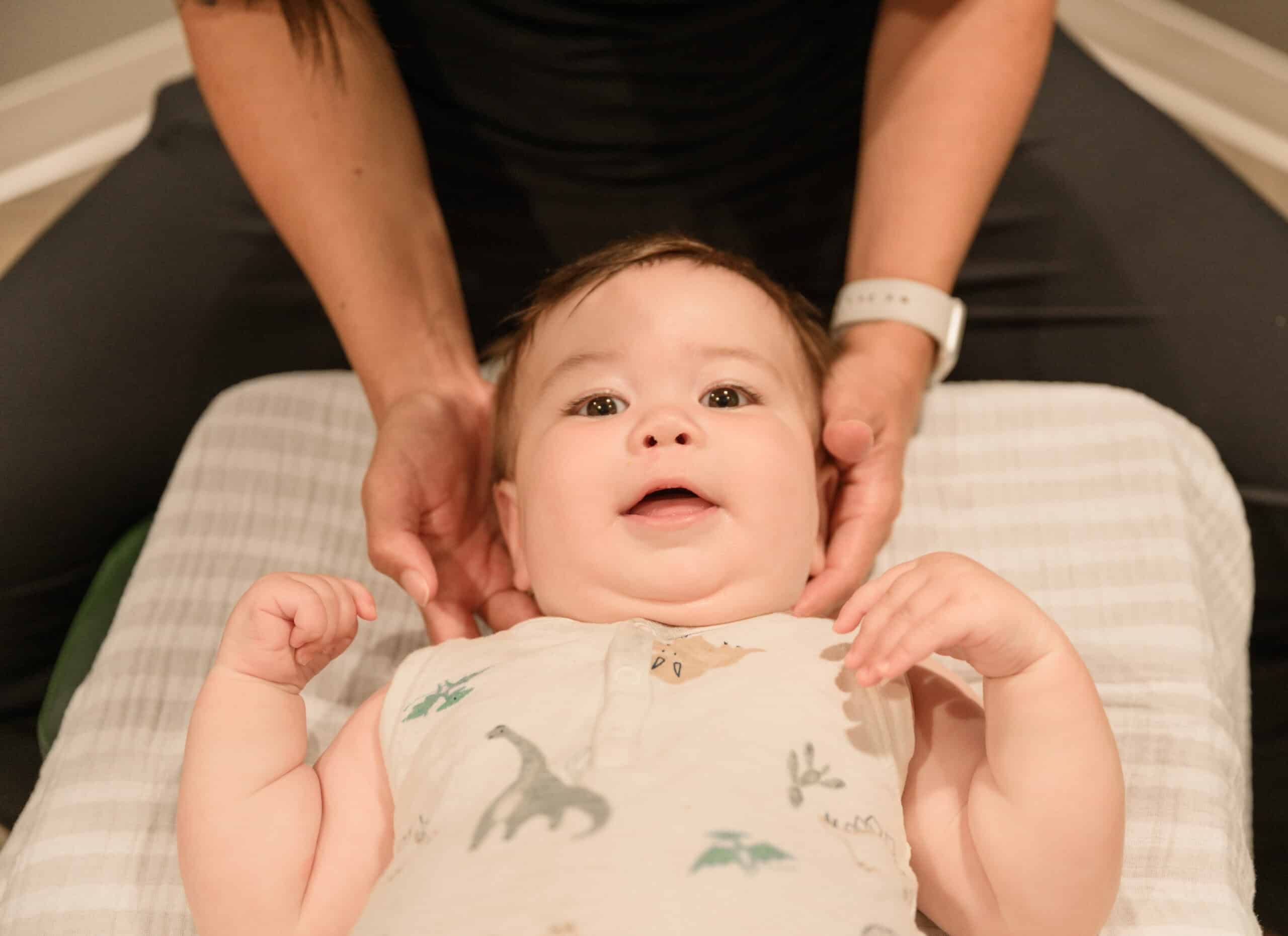 Gentle chiropractic adjustment on a smiling baby to promote healthy spine development and overall wellness for infants. Trusted pediatric chiropractic care at Lincoln Family Chiropractic.
